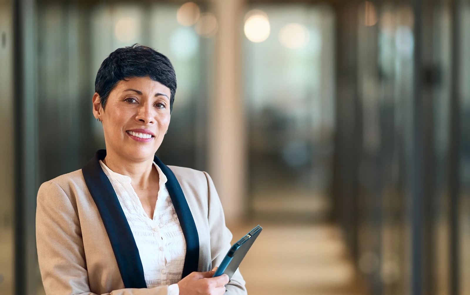 Smiling business professional holding a mobile phone in a modern office setting