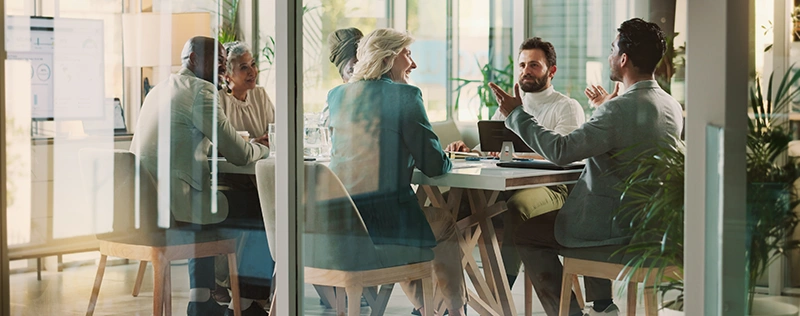 Team of professionals collaborating during a meeting in a glass-walled conference room